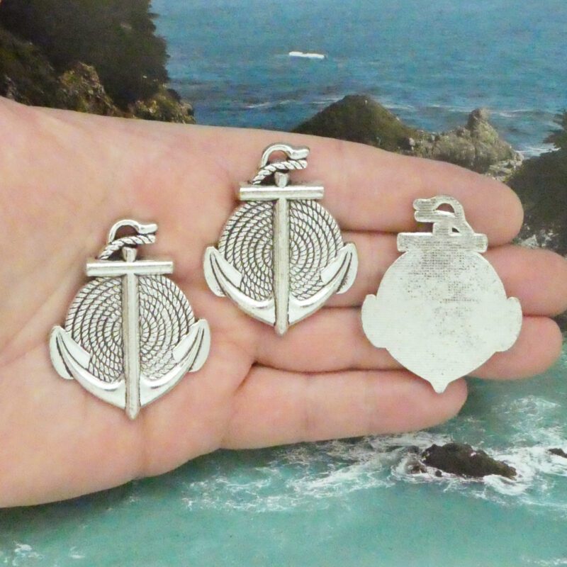 Additional photo of multiple forward-facing silver anchor charms and one turned around to show smooth charm back
